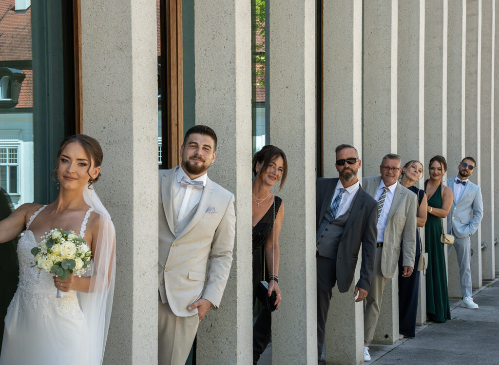 Gruppenbild: Das Brautpaar und die Familienmitglieder stehen jeweils an einer Säule des Museums für moderne Literatur in Marbach.